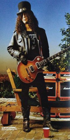 a man sitting on top of a bench holding a guitar