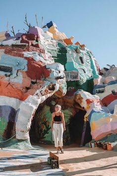 a woman standing in front of a colorful rock formation