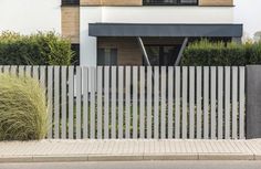 a house with a white picket fence in front of it and grass on the side