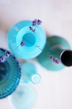 three blue vases with purple flowers in them