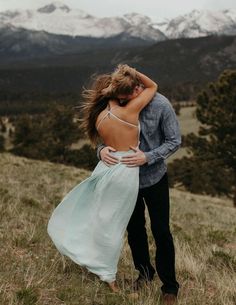 a man and woman embracing in the mountains