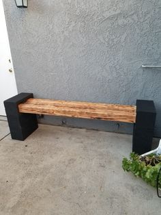 a wooden bench sitting on the side of a building next to a potted plant