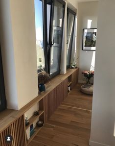 an empty room with wooden floors and windows on the wall, looking out onto the city