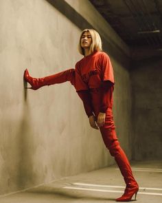 a woman in red is leaning against a wall