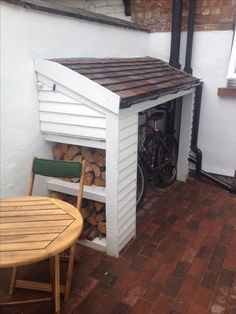 there is a bike in the shed next to some firewood and a table with two chairs