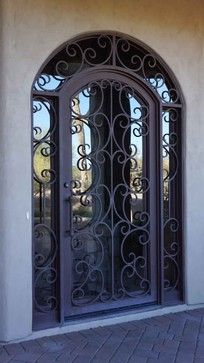 an iron gate is shown in front of a stucco wall and brick patio with potted plants on the side