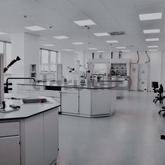 an empty laboratory with white cabinets and black counter tops is seen in this image, there are several lab chairs around the island