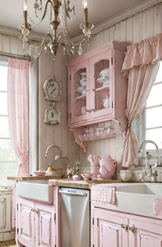 a pink kitchen with lots of cupboards and dishes on the counter top, including a dishwasher