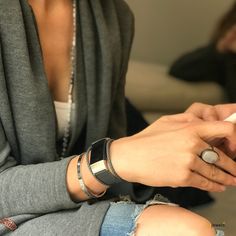 a woman is sitting on the floor using her cell phone and looking at her watch