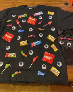 a black t - shirt with candy and candies on it sitting on top of a wooden floor