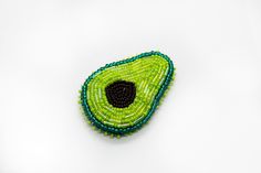 an avocado beaded brooch sits on a white surface