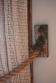 an image of a rope hanging on the wall next to a wooden block with a knot in it