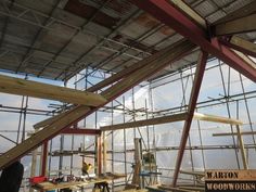 the inside of a building that is being built with wood and glass on the roof