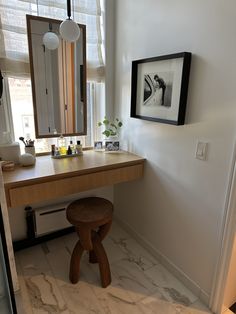 a bathroom with a vanity and stool next to a window in front of the mirror