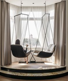 a woman sitting on a swing chair in front of a window