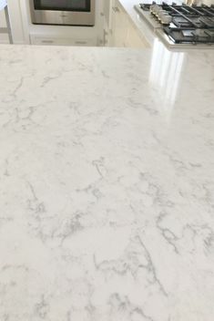 a white marble counter top in a kitchen with stainless steel stove and oven behind it