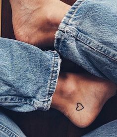 two people with tattoos on their feet sitting next to each other and one has a heart tattooed on the foot