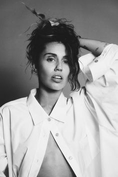 a black and white photo of a woman with her hair blowing in the wind while wearing a shirt