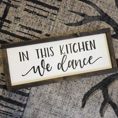 a sign that says in this kitchen we dance on the floor next to a rug