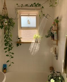 a bath tub sitting under a window next to a plant filled bathroom sink with plants growing on the wall