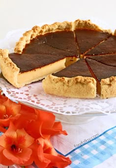 there is a pie on the table with flowers in the foreground and an orange flower next to it