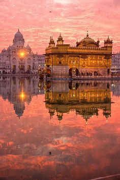 the golden temple in amritra india is reflected in the still water at sunset