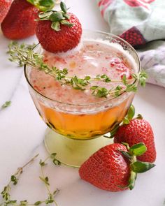 two strawberries on top of a drink in a glass with ice and garnish