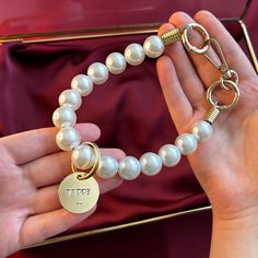 a person holding onto a bracelet with pearls and a gold plated charm on it