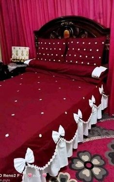 a bed with red sheets and white bows on it