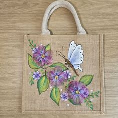 a bag with flowers and a butterfly painted on the front is sitting on a wooden surface