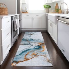 a kitchen with white cabinets and wood flooring is decorated in blue, orange and gold marble