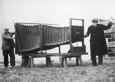 an old photo of two men standing next to a large object