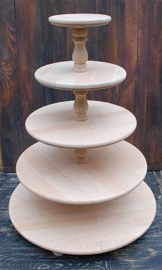 three tiered cake stand on top of a wooden table in front of a wood wall