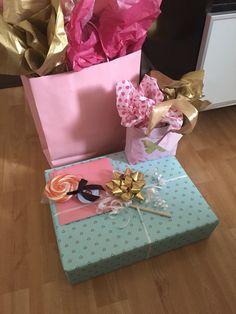 two wrapped presents sitting on top of a wooden floor next to some pink and gold wrapping paper