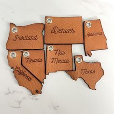 leather state tags with names on them sitting on a counter top in front of a white background