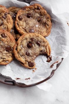 four chocolate chip cookies sitting on top of a piece of wax paper next to a fork