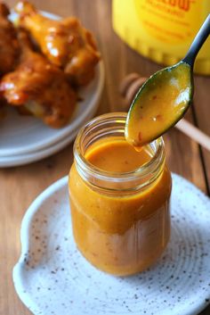 a spoon full of peanut butter on top of a plate with chicken wings in the background