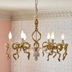 a chandelier hanging from the ceiling in a room with pink walls and wallpaper