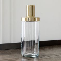 a clear glass bottle with a gold top on a wooden table