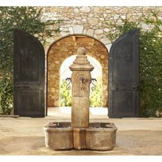 an outdoor fountain in the middle of a courtyard with arched doorways and stone walls