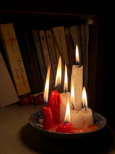 lit candles are on a plate in front of books