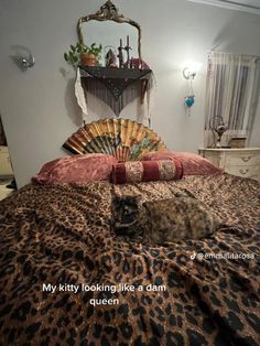 a cat laying on top of a leopard print bed