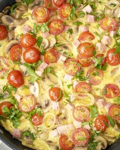 an omelet with tomatoes, mushrooms and ham in a cast iron skillet