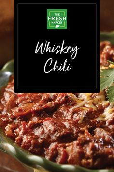 the fresh market whiskey chilli is in a green bowl with cilantro on top