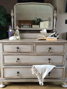 an old dresser with a mirror, books and a towel on it's top