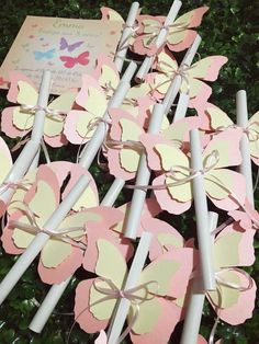 some pink and white butterflies on sticks with a card in the middle, surrounded by greenery