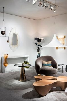 a living room filled with furniture next to a wall mounted mirror and lamp hanging from the ceiling