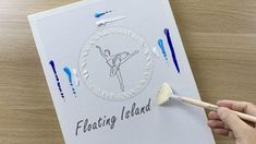 a hand holding a paintbrush over a card with the words floating island on it