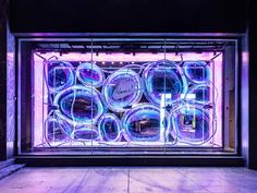 an empty storefront with neon lights on the front and side windows that have round glass panes in them