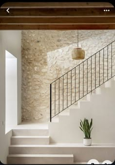 a white staircase with a potted plant next to it and a light fixture hanging from the ceiling